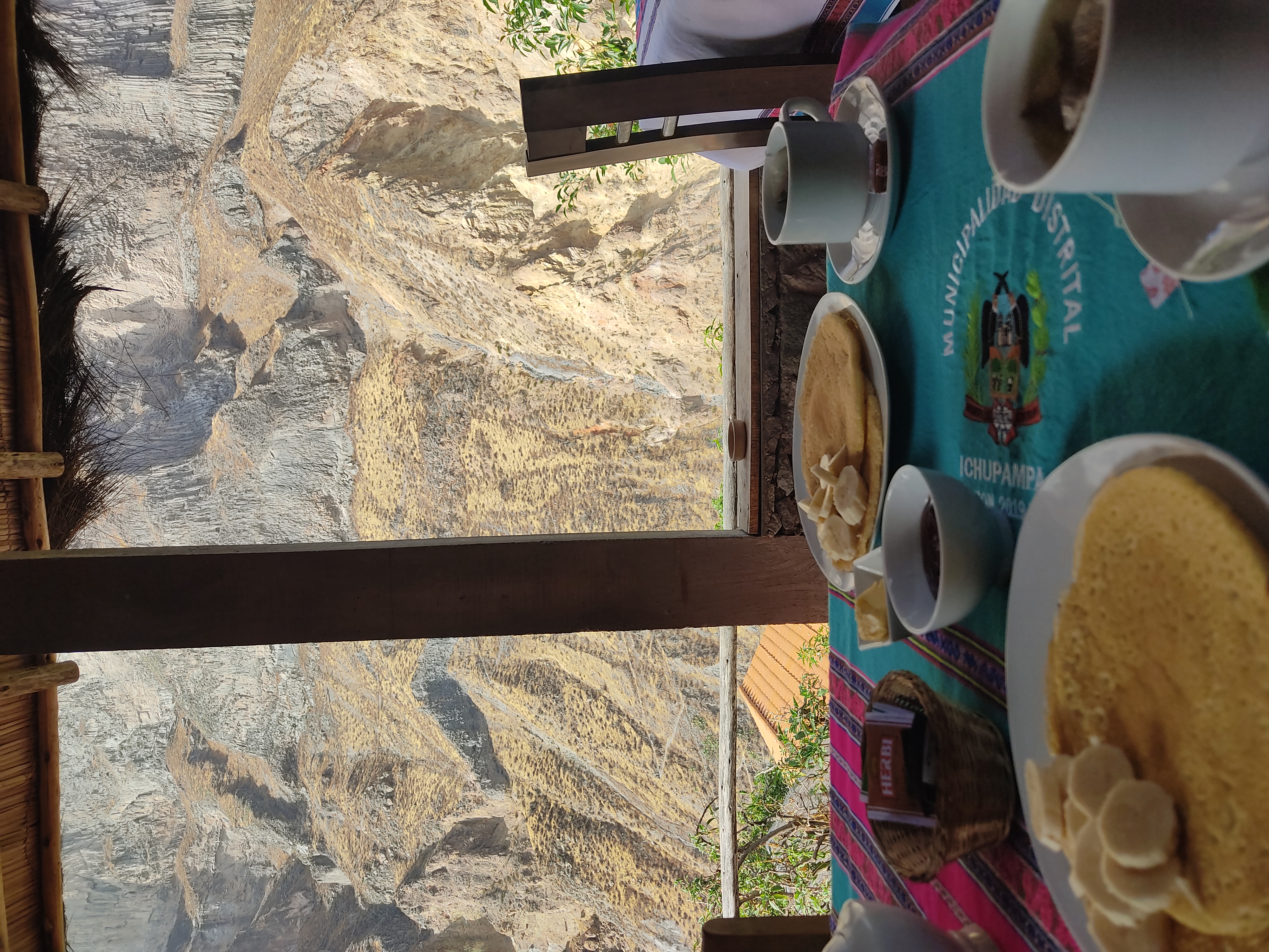 A breakfast table with tea and pancakes and banana, overlooking the canyon