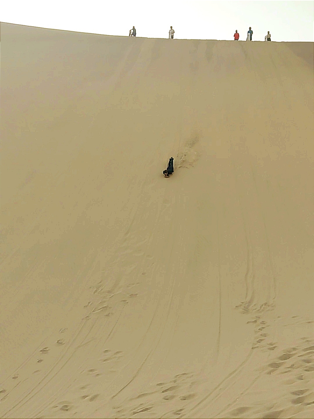 Sandboarding down the sand dunes on a snow board at Huacachina